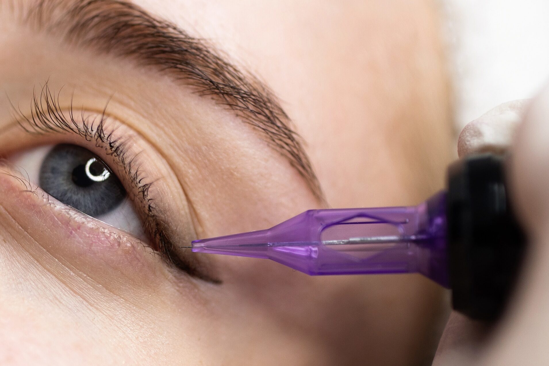 Micropigmentation Concept. Beautician doing permanent make up eyeliner procedure to young woman